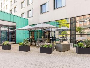 a patio with tables and umbrellas in front of a building at Novotel Hamburg City Alster in Hamburg
