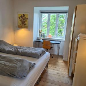 a bedroom with two beds and a desk and a window at Bjerregade Horsens Centrum in Horsens