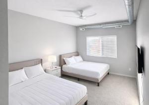 a white bedroom with two beds and a window at Casa Marigold in Des Moines