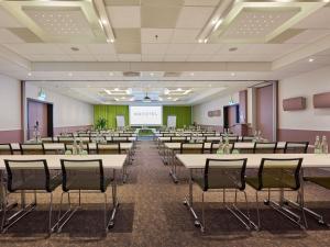 ein Konferenzraum mit Tischen, Stühlen und einer Leinwand in der Unterkunft Novotel Bern Expo in Bern