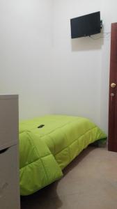 un letto verde in una stanza con una TV sul muro di Incontro Montoro Guest House & Restaurant a Montoro Inferiore