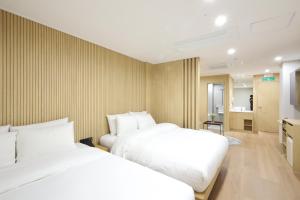 two beds in a hotel room with white sheets at Busan Seomyeon Nestly Hotel in Busan +75 photos