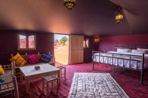 Zimmer mit 2 Betten, einem Tisch und einem Sofa in der Unterkunft Ali & Sara's Desert Palace in Merzouga