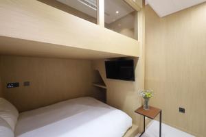 a small bedroom with a bed and a tv at Busan Seomyeon Nestly Hotel in Busan