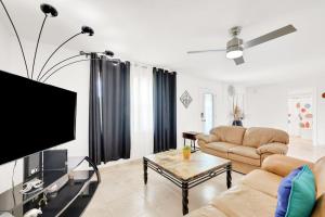 a living room with a couch and a flat screen tv at Three Palms Retreat in Cape Coral +25 photos