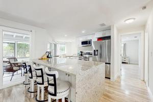 a white kitchen with a large island with bar stools at The Flip Flop Stop in Naples +17 photos