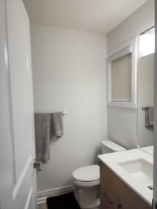 a white bathroom with a toilet and a sink at Edmonton 3BR House in Edmonton