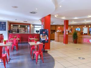a restaurant with red tables and chairs and a bar at Ibis Madrid Alcorcon Tresaguas in Alcorcón