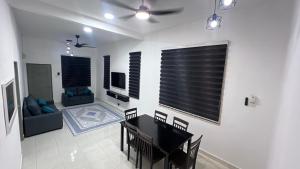 a living room with a table and chairs and a television at Razumi's Homestay 3 in Arau