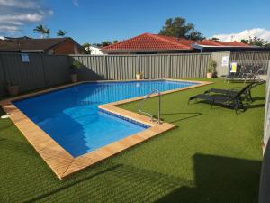 a swimming pool in a yard with green grass at Port O'Call Motel in Port Macquarie