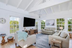 a living room with white furniture and a flat screen tv at Bocilla Breeze in Bokeelia