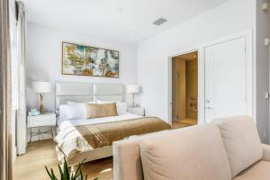 a white bedroom with a bed and a couch at SoCe Flats 209 in Naples