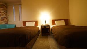 two beds in a hotel room with a light between them at Hotel New Gaea Itoshima in Itoshima