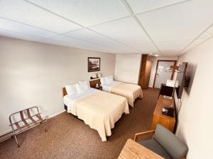 a hotel room with two beds and a chair at Lake Ontario Motel & Inn in Newfane