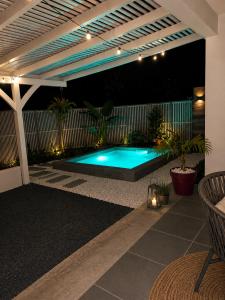a swimming pool in the middle of a patio at night at Golden palm in Rivière-Pilote
