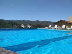 a swimming pool with chairs and blue water at Cabañas Wairoa Haus 6 ctas sin interés!!!! in Villa General Belgrano