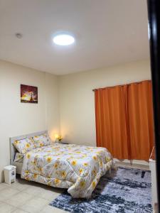a bedroom with a bed and an orange curtain at Abdulla al Shaiba in Jazīrat al Ḩibāb