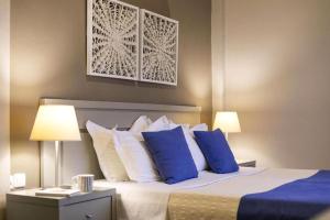a bedroom with a bed with blue and white pillows at Nimfi Hotel, Skiathos in Megali Ammos
