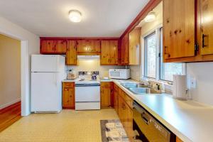 a kitchen with wooden cabinets and a white refrigerator at Corner Cottage in Chatham +11 photos