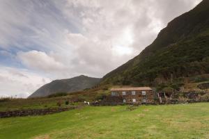 a house in the middle of a field in a mountain at Caldeira Guesthouse in Fajã da Caldeira de Santo Cristo