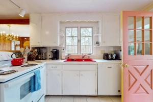 a kitchen with white cabinets and a pink door at Herring Brook in Eastham +16 photos