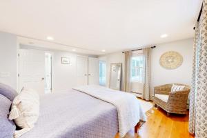 a white bedroom with a bed and a chair at Lisa Lane in Mashpee