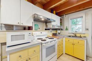 a white kitchen with white appliances and yellow cabinets at TumbleINN in Oak Bluffs