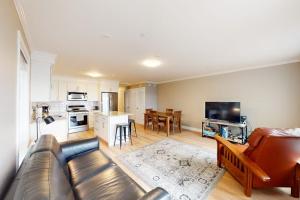 a living room with a leather couch and a kitchen at Summer Cape Escape in Dennis Port