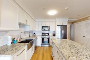 a large kitchen with white cabinets and granite counter tops at Summer Cape Escape in Dennis Port