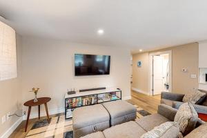 a living room with a couch and a tv on the wall at The Cape House in Cotuit