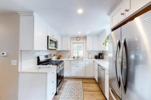 a white kitchen with white cabinets and a refrigerator at The Cape House in Cotuit