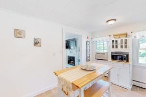 a kitchen with white cabinets and a wooden table at Downtown Seaside Serenity Retreat in Hyannis +12 photos