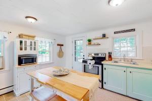 a kitchen with white cabinets and a wooden table at Downtown Seaside Serenity Retreat in Hyannis