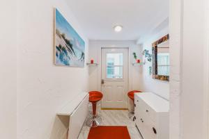 a white room with a desk and a red stool at Captivating Cottage in Provincetown +10 photos