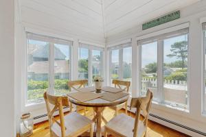 a dining room with a table and chairs and windows at Shoreline Escape in Mashpee