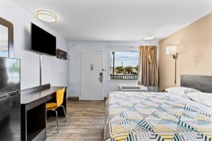 a hotel room with a bed and a desk and a television at Studio 6 Wilmington, NC in Wilmington