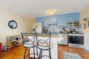 a kitchen with blue cabinets and two bar stools at The Blue Cottage in Provincetown