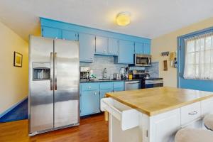 a kitchen with blue cabinets and a stainless steel refrigerator at The Blue Cottage in Provincetown