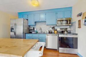 a kitchen with blue cabinets and a wooden table at The Blue Cottage in Provincetown +7 photos