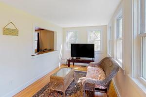a living room with a television and a chair at Belmont Beach Cottage in West Harwich