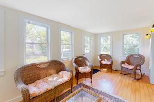 a living room with wicker furniture and windows at Belmont Beach Cottage in West Harwich
