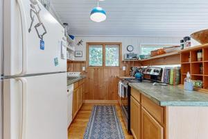 a kitchen with a white refrigerator and wooden cabinets at Drummer Cove Retreat in Wellfleet +17 photos