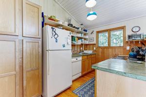 a kitchen with a white refrigerator and wooden cabinets at Drummer Cove Retreat in Wellfleet
