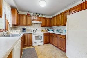a kitchen with wooden cabinets and a white refrigerator at Sandpiper's Saltbox in Dennis +12 photos