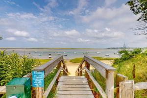 a wooden staircase leading to a beach with boats in the water at Gray Gables in Orleans