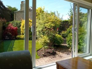 an open window with a view of a garden at Abbeyside Cottage in Kelso