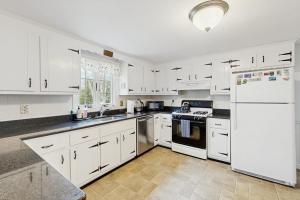 a kitchen with white cabinets and a white refrigerator at Captain's Escape in South Yarmouth +11 photos