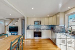 a kitchen with white cabinets and a table with chairs at Seabreeze Escape in Falmouth +14 photos