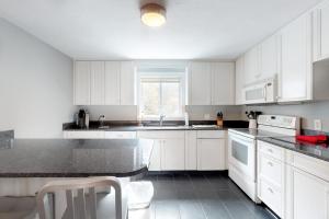 a kitchen with white cabinets and a black counter top at Need a Bigger Boat in Edgartown