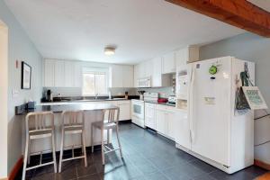 a kitchen with white cabinets and a white refrigerator at Need a Bigger Boat in Edgartown +32 photos